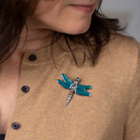 a close up of a model wearing a camel-colored sweater adorned with the dragonfly brooch