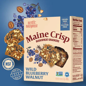 Maine Crisp Wild Blueberry Walnut Crisps box against a blueberry blue background with images of ingredients