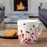 the winterberries mug on a wood table with a small plate of cookies in a living room with a fireplace