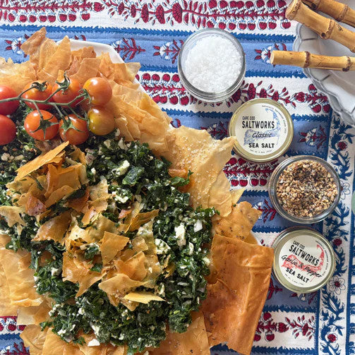 a colorful spanakopita dish featured alongside jars of garlic & pepper sea salt and classic sea salt 