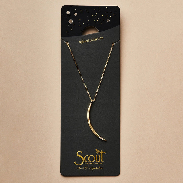 a slender gold pendant in the shape of a slice of the moon in its gibbous phase with 3 mini CZ stones on the bottom curve on a black card that serves as its packaging and shows more of the chain length