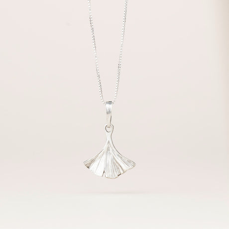 an intricately detailed pewter ginkgo leaf shaped pendant hanging from a silver chain