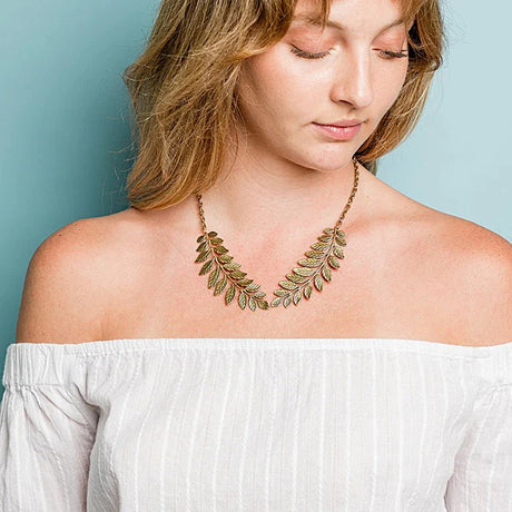 Woman wearing a leaf-shaped necklace against a light blue background
