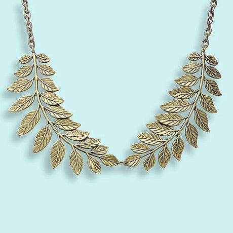 Gold leaf necklace on a light blue background