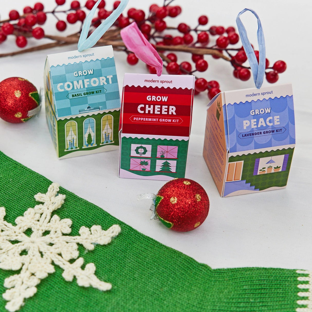 a trio of colorful house shaped ornaments amongst other holiday decorations