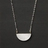 A silver necklace with a half moon pendant
