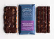 three Night at the Movies bars side by side - two unwrapped bars with a wrapped one in the center. Rich dark chocolate is pebbled with whole almonds, the chocolate bar wrapper is royal blue with a purple label with product info