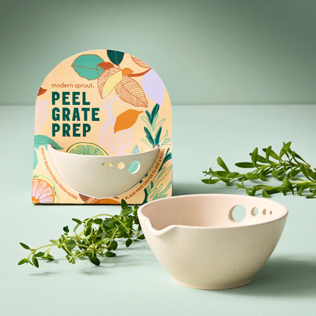 the peel grate & prep dish on a table next to some fresh thyme and the dish in its packaging