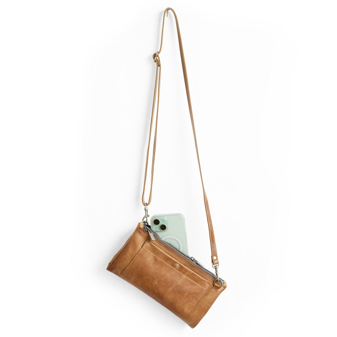 Brown leather crossbody bag with a phone inside on a white background