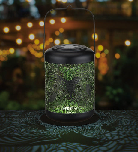 Large hummingbird shadow lantern in a garden setting, beautifully illuminating the outdoor space.