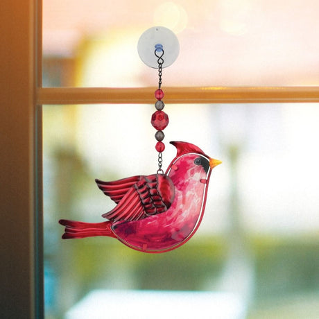 a charming red cardinal suncatcher with beaded chain hanging from a suction cup shown hanging from a glass window