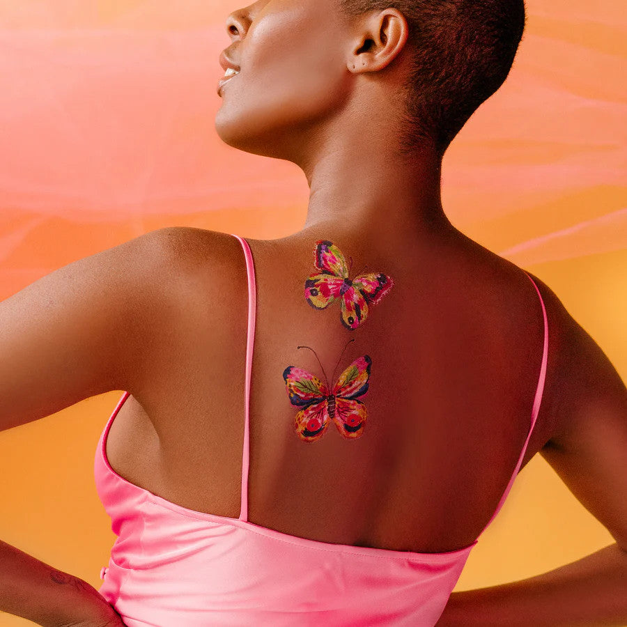 a model's upper back and shoulders with several of the butterfly tattoos applied