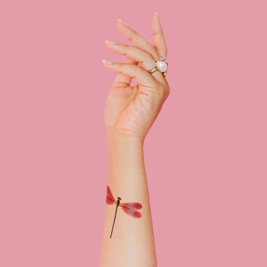 a model's arm pointed upward with the amber damselfly tattoo applied to the inner forearm