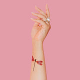 a model's arm pointed upward with the amber damselfly tattoo applied to the inner forearm