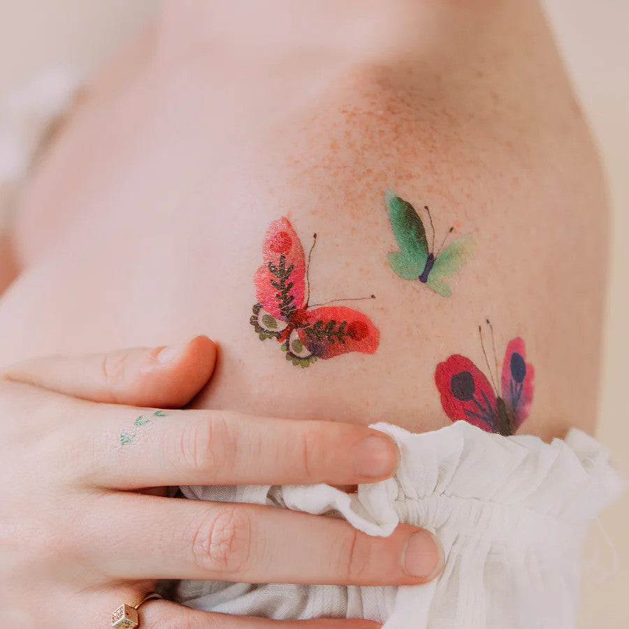 a model's upper arm with a few of the colorful butterfly tattoos applied