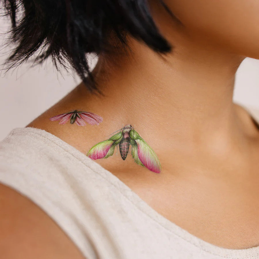 close up of a model's neck and collarbone showing two tattoos applied just above her collarbone