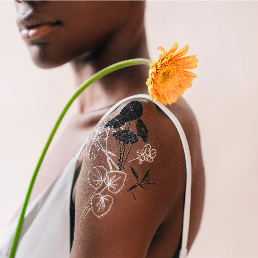 a model in profile showing the glowing garden tattoos applied to her upper arm