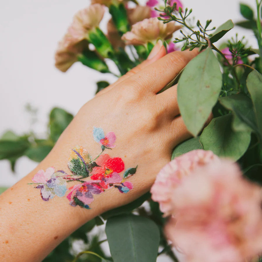 a closeup of a model's hand with one of the vibrant watercolor floral tattoos applied