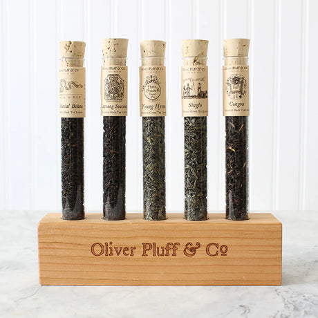5 corked glass tubes of loose leaf tea blends on a wood display block with the brand "Oliver Plufff & Co on the front of it