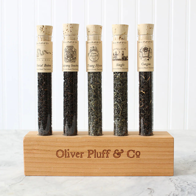 5 corked glass tubes of loose leaf tea blends on a wood display block with the brand "Oliver Plufff & Co on the front of it