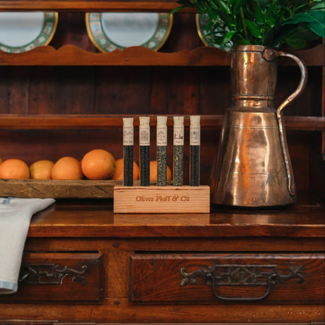 The teas of the Boston Tea Party in their display block on a colonial era kitchen hutch alongside a copper pot and plate of oranges